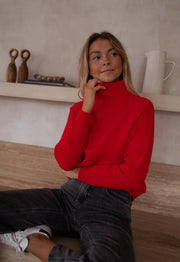 Pull rayé col montant zippé porté par une femme, vue de trois-quarts, regard de côté