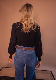 Pull à manches légèrement bouffantes porté par une femme, vue de dos, ceinture marron, jean