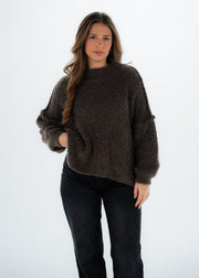 Pull bouclé taupe — vue portée de face en studio, cadrée à la taille, pantalon noir