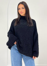Pull bouclé noir — vue portée de face, cadrée à la taille, col roulé et jean clair