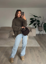 Pull bouclé taupe — selfie au miroir, devant une plante et un canapé