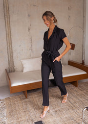 Combinaison fluide à col chemise portée par une femme, vue de trois-quarts, canapé, tapis
