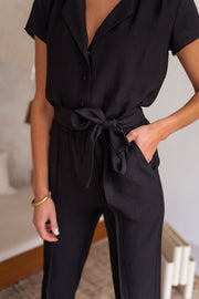 Combinaison fluide à col chemise portée par une femme, vue rapprochée, ceinture nouée, main dans la poche