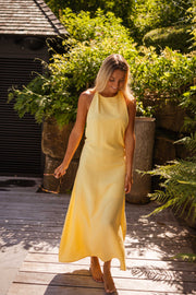 Robe longue à dos ouvert portée par une femme, vue de face, cheveux blonds, terrasse