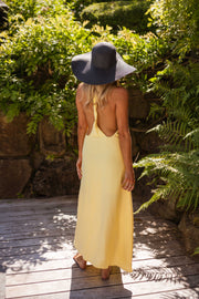 Robe longue à dos ouvert portée par une femme, vue de dos, chapeau, terrasse en bois