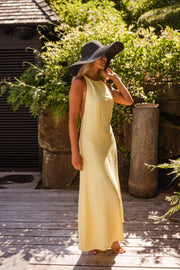 Robe longue à dos ouvert portée par une femme, vue de profil, chapeau noir, main sur l'oreille
