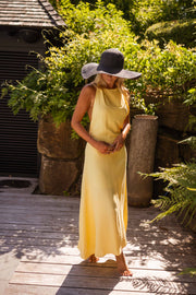Robe longue à dos ouvert portée par une femme, vue de face, chapeau, terrasse