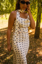 Robe à pois effet soie portée par une femme, vue de trois-quarts, lunettes de soleil, foulard