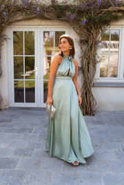Robe à col montant fleuri portée par une femme, vue de face, porte-fenêtre, sac à main