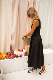 Robe longue buste moulant portée par une femme, vue de dos, panier en paille, fruits