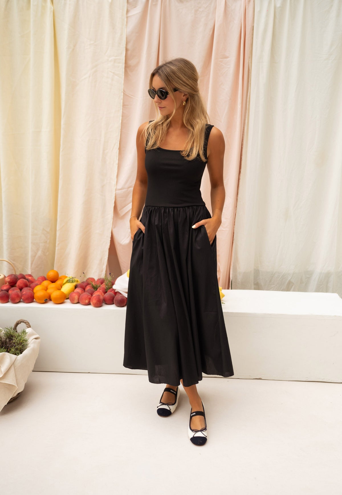 Robe longue buste moulant portée par une femme, vue de face, rideaux, poches