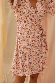 Robe fleurie cache-cœur courte portée par une femme, vue rapprochée, nœud à la taille, cache-cœur