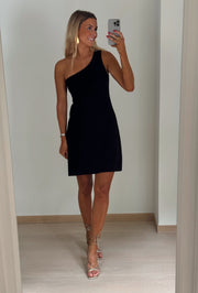 Robe courte en maille asymétrique portée par une femme, vue de face, selfie, mur blanc