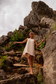 Robe en tweed à sequins portée par une femme, en marchant, rochers, bras écartés