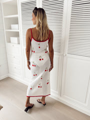 Robe crochet à cerises brodées portée par une femme, vue de face, placard à persiennes, bordure rouge