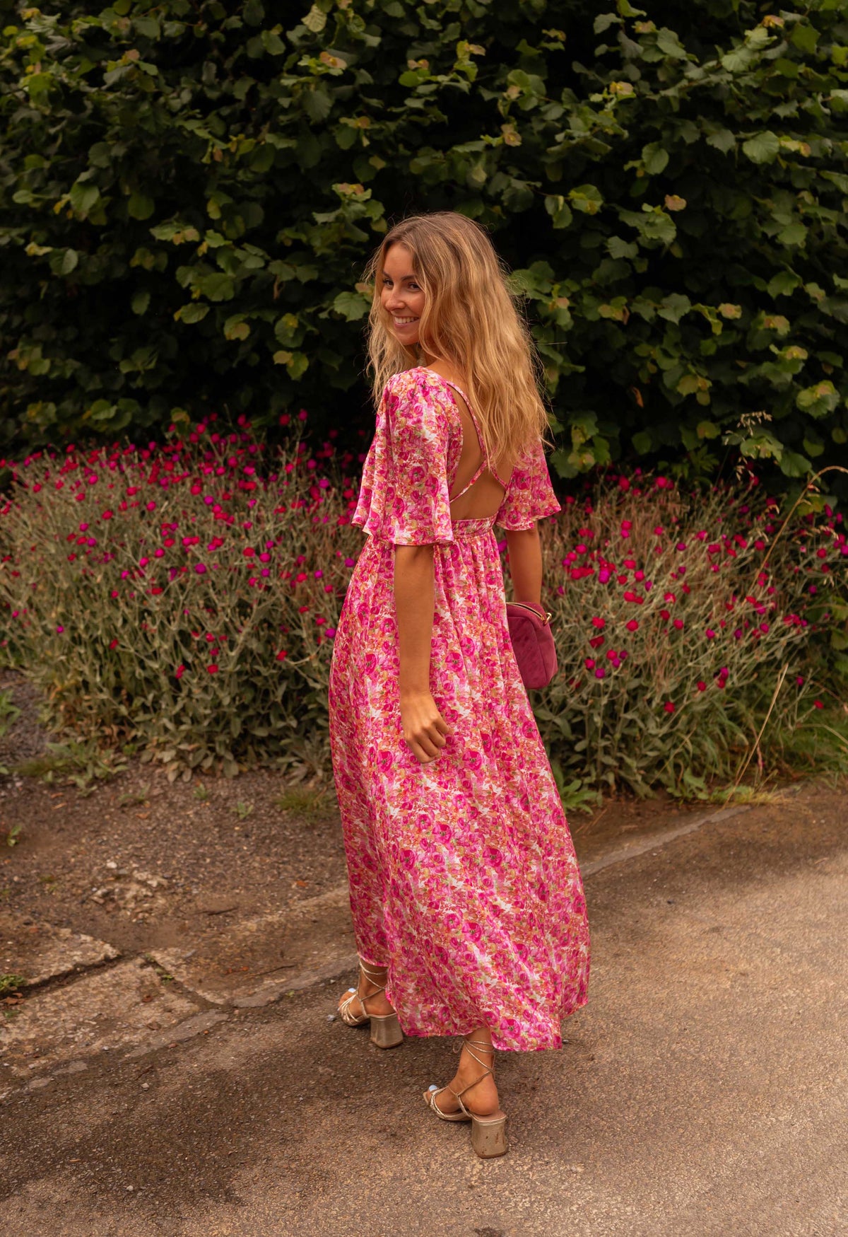 Robe fleurie à dos ouvert portée par une femme, vue de dos, allée, fleurs roses