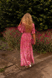 Robe fleurie à dos ouvert portée par une femme, vue de dos, haie, allée