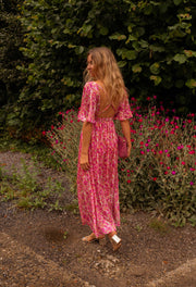 Robe fleurie à dos ouvert portée par une femme, vue de dos, massif de fleurs, jupe