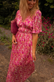 Robe fleurie à dos ouvert portée par une femme, vue rapprochée, décolleté V, manches bouffantes
