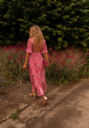 Robe fleurie à dos ouvert portée par une femme, vue de dos, haie, cheveux blonds