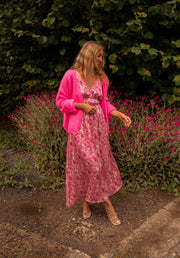 Robe fleurie à dos ouvert portée par une femme, en marchant, gilet rose, sac