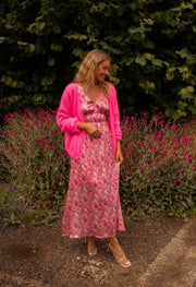 Robe fleurie à dos ouvert portée par une femme, vue de face, gilet rose, parterre