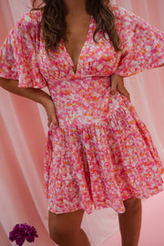 Robe fleurie à manches courtes portée par une femme, vue rapprochée, décolleté V, manches papillon