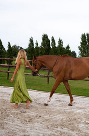 Robe longue à fermeture éclair portée par une femme, en marchant, cheval en main, prairie