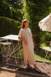 Robe éponge à manches courtes portée par une femme, silhouette entière, table blanche, jardin