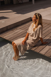 Robe éponge à manches courtes portée par une femme, assise, bassin, pieds dans l'eau