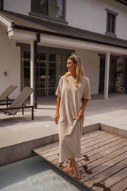 Robe éponge à manches courtes portée par une femme, vue de face, transats, ponton