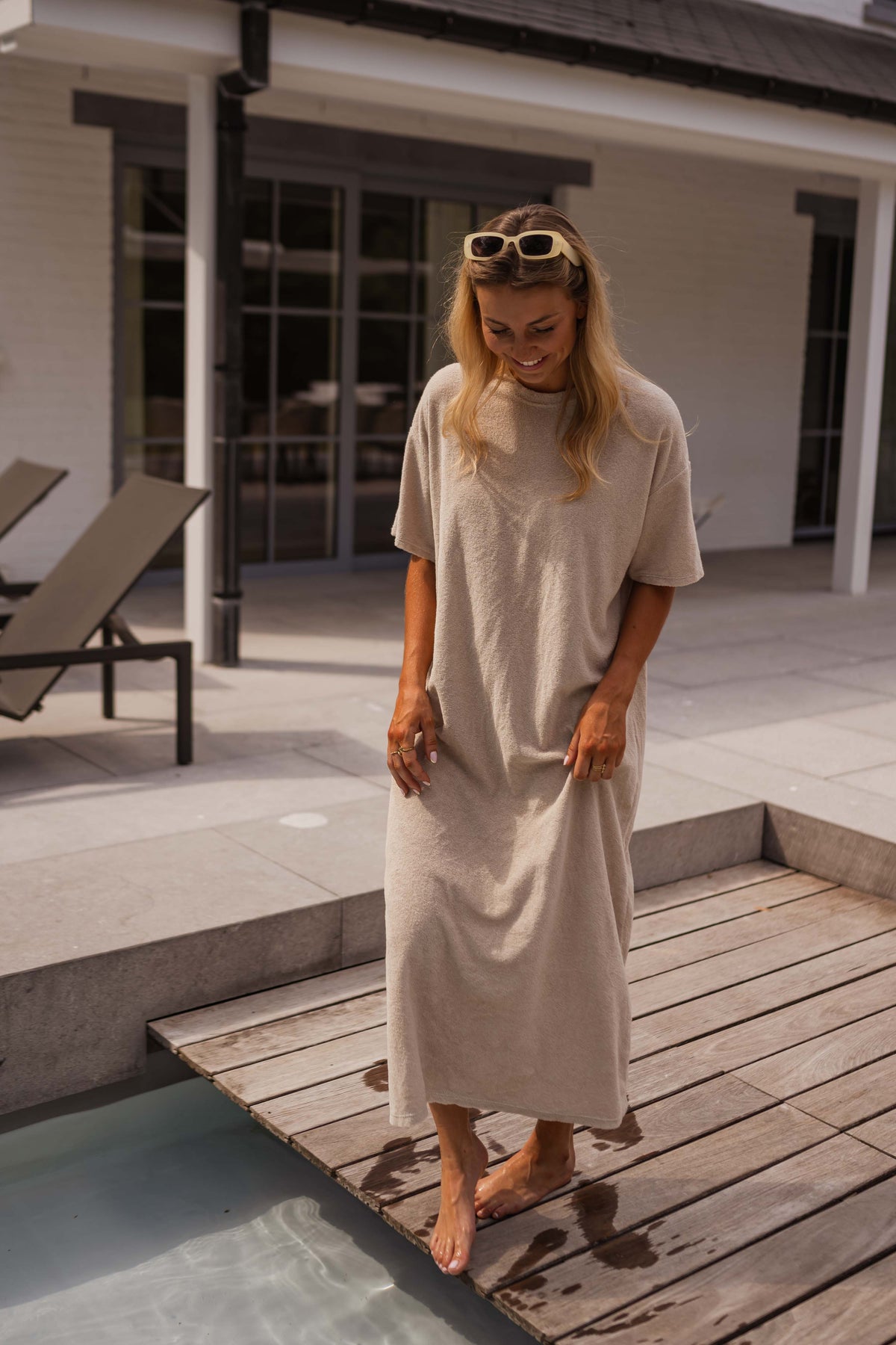 Robe éponge à manches courtes portée par une femme, vue de face, lunettes sur la tête, ponton
