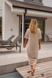 Robe éponge à manches courtes portée par une femme, silhouette entière, transats, maison