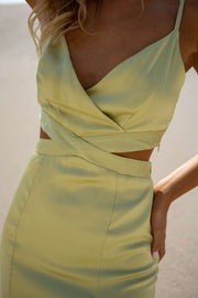 Robe longue effet soie verte portée par une femme, vue rapprochée, haut croisé, découpe à la taille