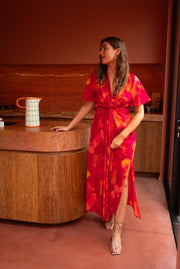 Robe longue col V fendue portée par une femme, vue de face, cuisine, main sur l'îlot