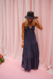 Robe longue à décolleté noué portée par une femme, vue de dos, chapeau, rideau rose
