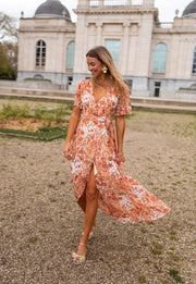 Robe longue portefeuille fleurie portée par une femme, en marchant, graviers, jupe qui vole