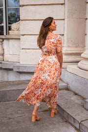 Robe longue portefeuille fleurie portée par une femme, vue de dos, escalier, jupe longue