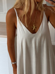 Robe en lin col V portée par une femme, vue rapprochée, col V, bretelles fines
