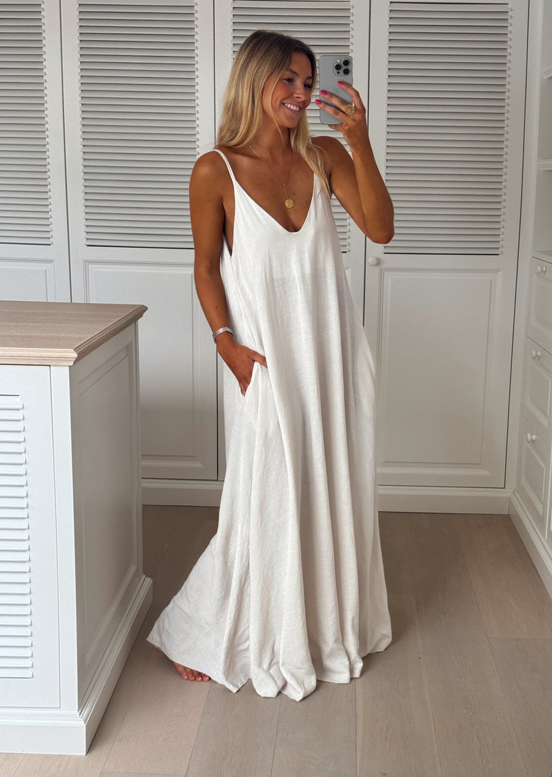 Robe en lin col V portée par une femme, silhouette entière, placard blanc, bretelles fines