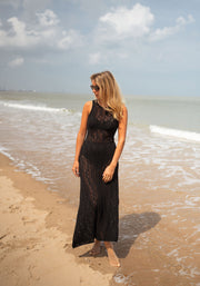 Robe crochet longue dos ouvert portée par une femme, vue de face, vagues, pieds nus