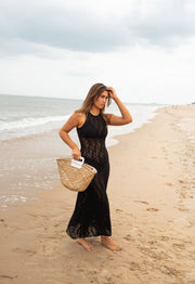 Robe crochet longue dos ouvert portée par une femme, vue de face, panier en paille, plage