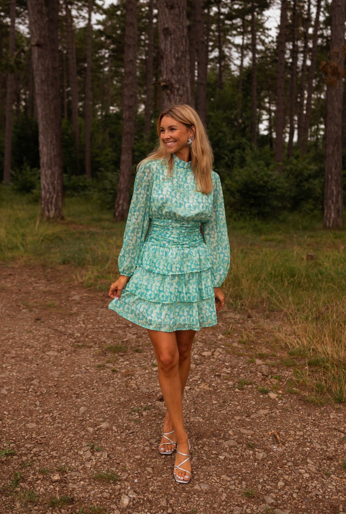 Robe fluide à motifs argentés portée par une femme, vue de face, forêt, sentier
