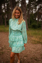 Robe fluide à motifs argentés portée par une femme, vue de trois-quarts, sentier, sourire