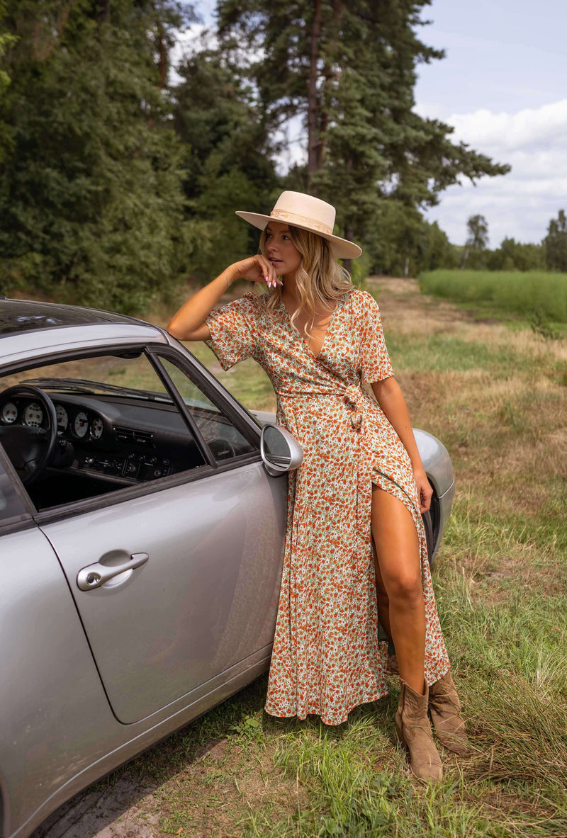 Robe portefeuille fleurie fluide portée par une femme, vue de face, voiture grise, chapeau de paille