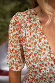 Robe portefeuille fleurie fluide portée par une femme, vue rapprochée, manches courtes, imprimé fleuri
