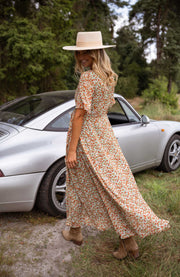 Robe portefeuille fleurie fluide portée par une femme, en marchant, chemin, chapeau de paille