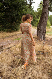 Robe portefeuille fleurie fluide portée par une femme, vue de dos, foin sec, arbre