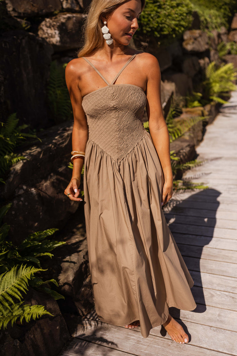 Robe effet smocké à nouer portée par une femme, silhouette entière, allée dallée, fougères