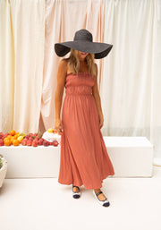 Robe bustier plissée devant portée par une femme, vue de face, grand chapeau, ballerines